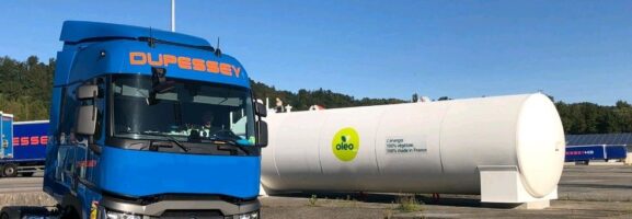 Camion Dupessey stationné à proximité d’une cuve Oleo100 sur un site logistique, sous un ciel bleu dégagé